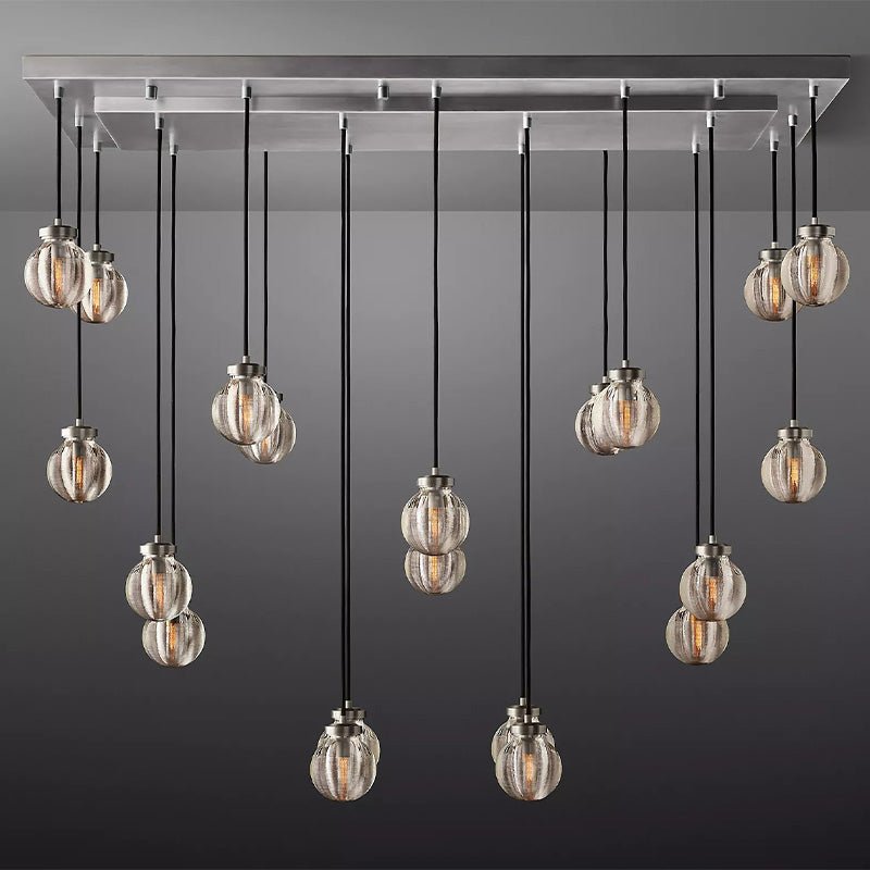 Linear chandelier with brushed nickel finish and clear ribbed glass globes suspended from black cords against gray background.